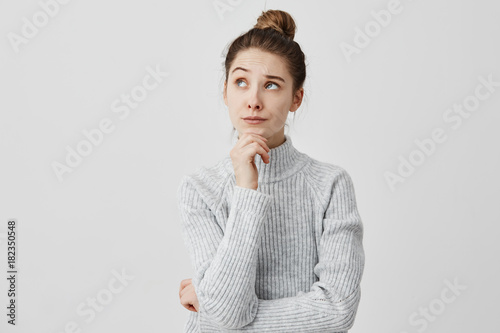 Tableau sur toile Young woman with dark hair holding her chin looking sideways