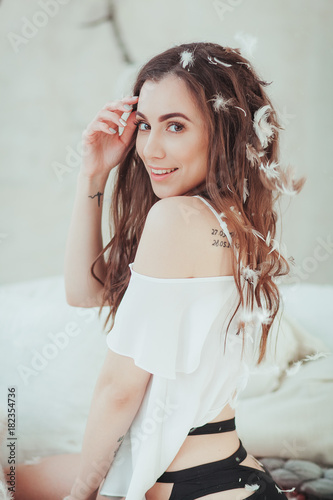 Portrait of beautiful young girl smiling in flying white feathers. clean soft body Beauty Woman Touching. Perfect Fresh Skin. Studio shot. Isolated on white wall background