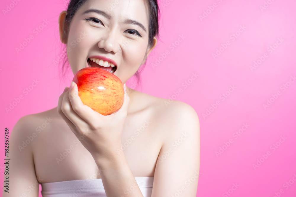 Asian woman with apple concept. She smiling and holding apple. Beauty face and natural makeup. Isolated over pink background. Asian woman with apple concept. She smiling and holding apple. Beauty face and natural makeup. Isolated over pink background.