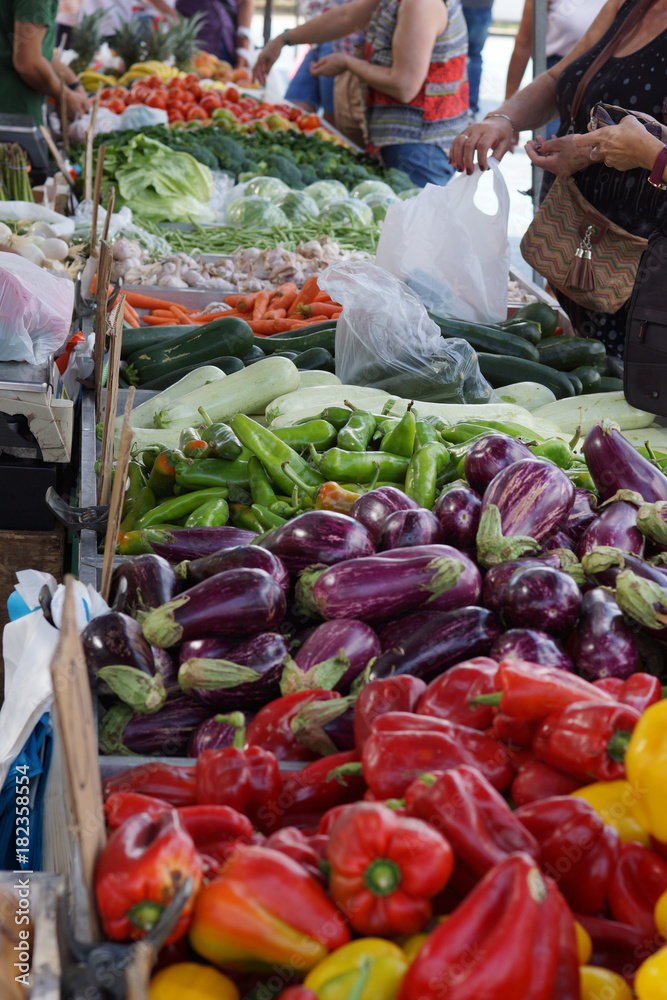 Customers choose the product in the vegetable market, on the counter pepper, eggplant and many other vegetables.