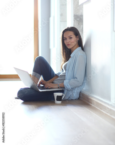 Young beautiful woman at home sitting on the floor with laptop. Young beautiful woman.