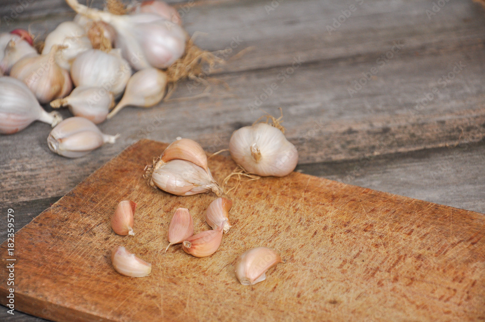 Garlic on old wooden board ready for cutting. Garlic Cloves and Garlic Bulb on on rustic cutting board