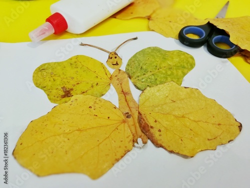 Children's hand-made from yellow autumn leaves in the form of a butterfly, children's creativity, photo