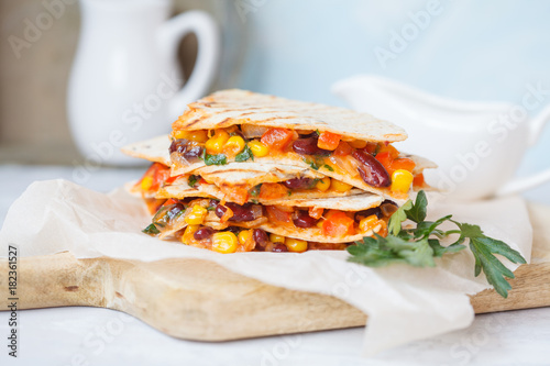 Vegetarian quesadilla with vegetables and cheese on a wooden board