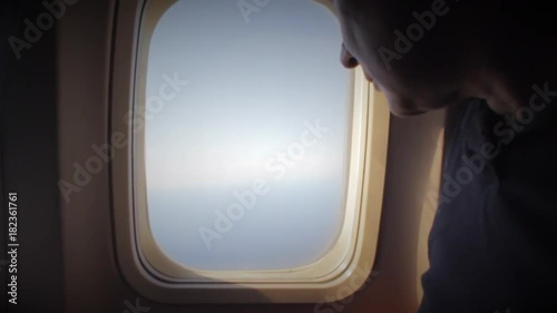 Man opens an airplane window and looks out during air travel. Happy. Man traveling by plane together. Tourism concept