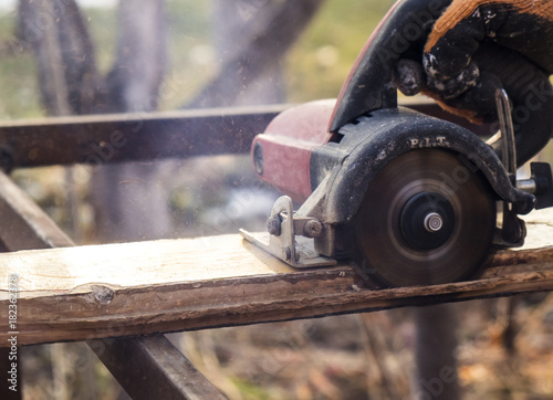 male hands with circular saw while workimg with wood
