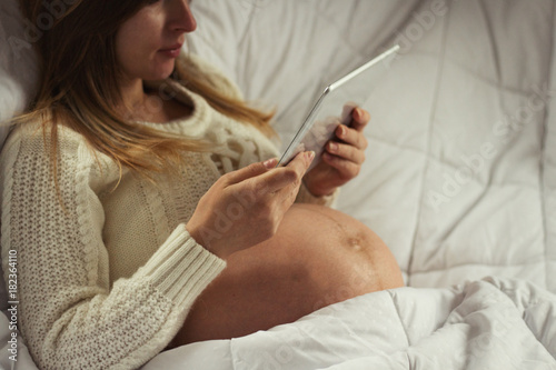 Pregnant young woman with a tablet, reads information infants