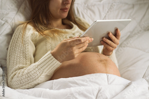 Pregnant with a tablet, reads the information of newborns