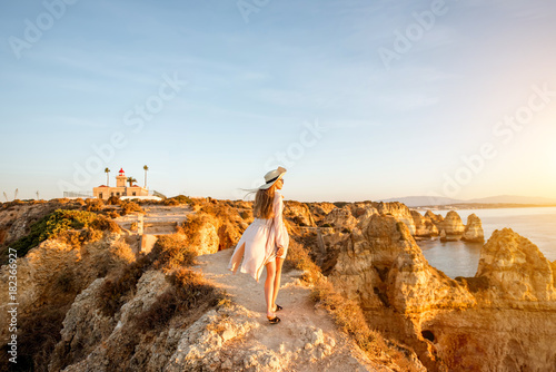 Woman enjoying great view on the rocky coastline during the sunrise in Lagos on the south of Portugal