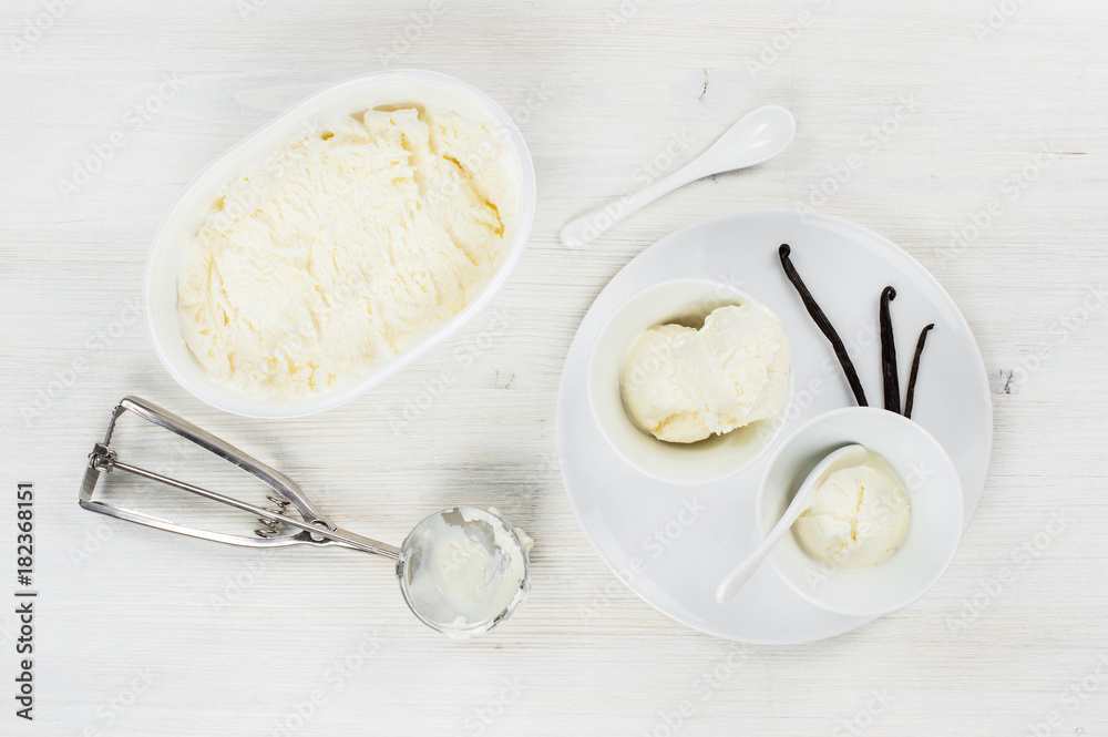 Two portions of vanilla ice-cream in the white plates on the wooden table