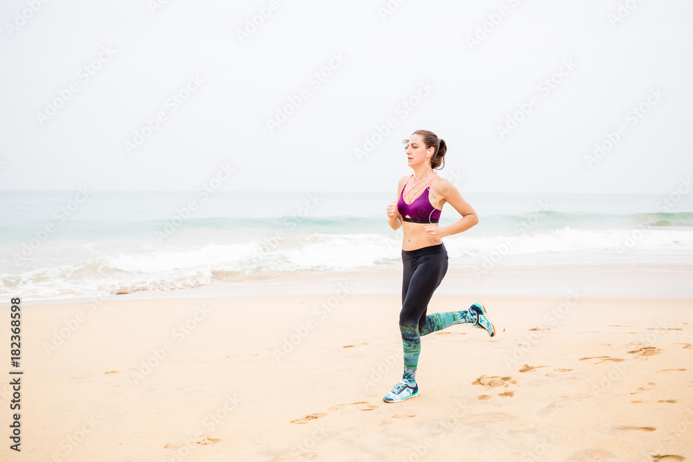 Woman is jogging along the seashore on an overcast day