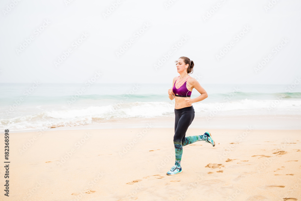 Woman is jogging along the seashore on an overcast day Woman is jogging along the seashore on an overcast day