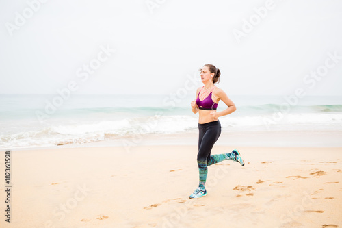 Woman is jogging along the seashore on an overcast day
