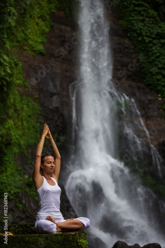 Woman practices yoga at Gitgit waterfall on Bali in indonesia