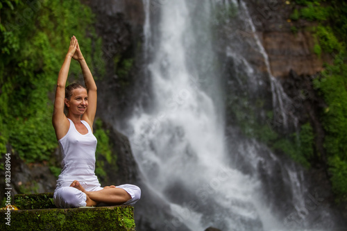 Woman practices yoga at Gitgit waterfall on Bali in indonesia