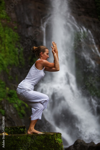 Woman practices yoga at Gitgit waterfall on Bali in indonesia