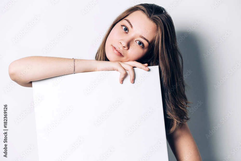 young smiling woman holding a blank sheet of paper for advertising, close-up young smiling woman holding a blank sheet of paper for advertising, close-up