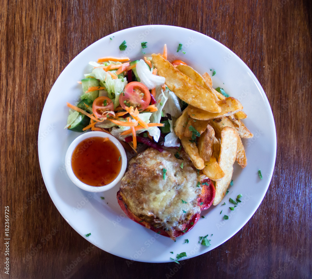 Red stuffed capsicum pepper with cheese, potato wedges, dipping sauce and fresh salad Red stuffed capsicum pepper with cheese, potato wedges, dipping sauce and fresh salad