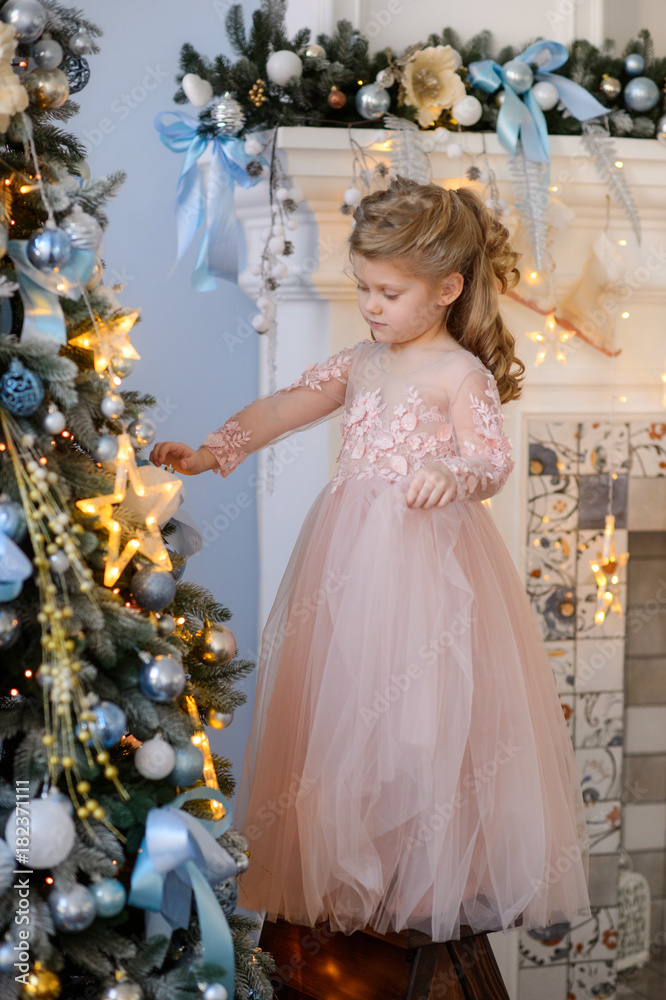 Merry Christmas celebration. Beautiful little girl in a amazing dress near the Christmas tree. Christmas miracles. Happy New Year