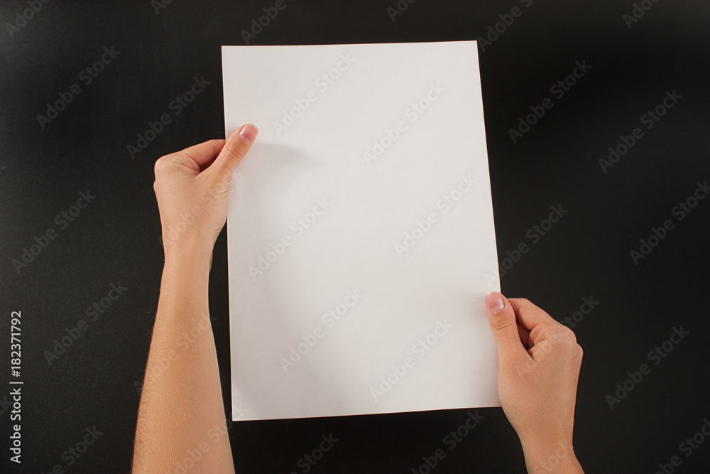 Female hands with paper on a black background. Studio
Female hands with paper on a black background. Studio