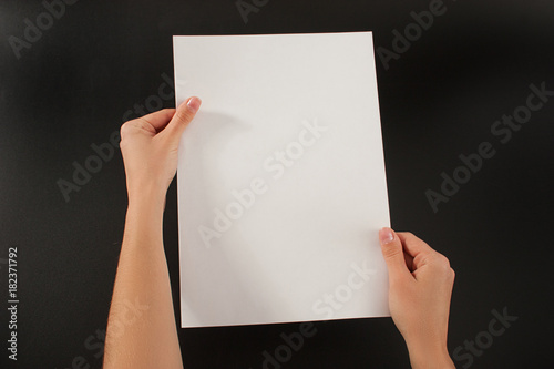 
Female hands with paper on a black background. Studio