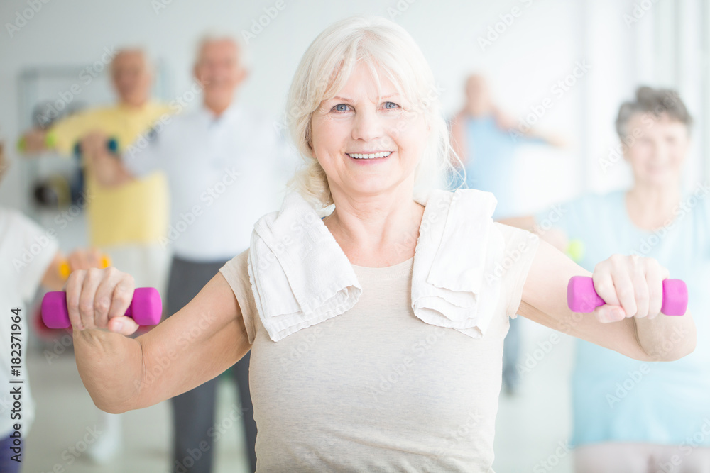 Fototapeta premium Elderly woman exercising with dumbbells