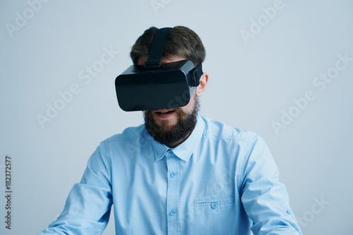 A man with a beard on a light blue background in virtual reality glasses