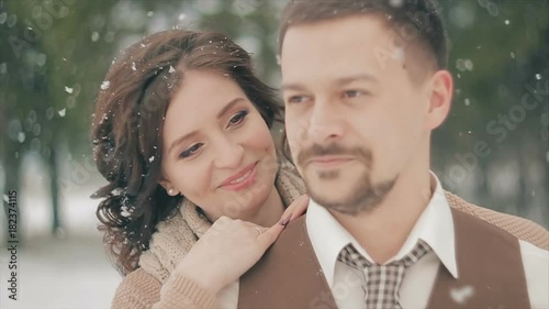 Young Wedding Couple Kissing on Snow Field on Winter Day. Rustic Style Wedding. Lovely Girl in Long Wedding White Dress, Green Pine Forest on Background. Brown Style Wedding. Slow Motion