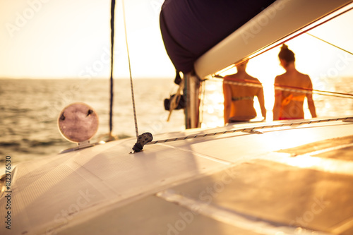Women in bikini on the sailing boat watching the sea and horizon, sunset mood