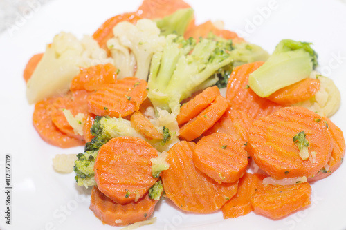 Fried vegetables on a white plate. Carrots, broccoli and cauliflower