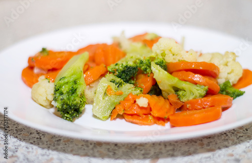 Fried vegetables on a white plate. Carrots, broccoli and cauliflower