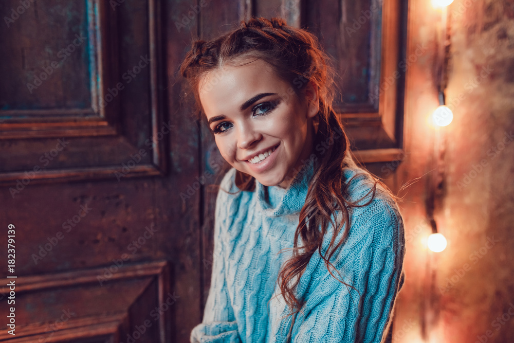 Fototapeta premium Portrait of a beautiful woman in a blue sweater. Christmas. New Year.
