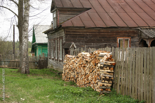 Old house in a Russian village with the prepared firewood for winter