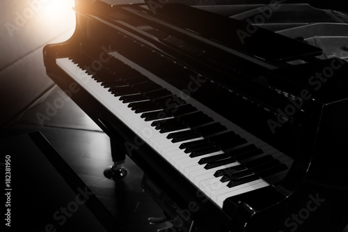 Fototapeta Czarny błyszczący fortepian z białą klawiaturą w ciemnym tonie