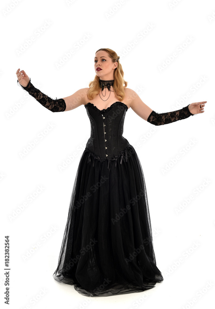 full length portrait of a blonde girl wearing black gothic gown. standing pose, isolated on white background. full length portrait of a blonde girl wearing black gothic gown. standing pose, isolated on white background.