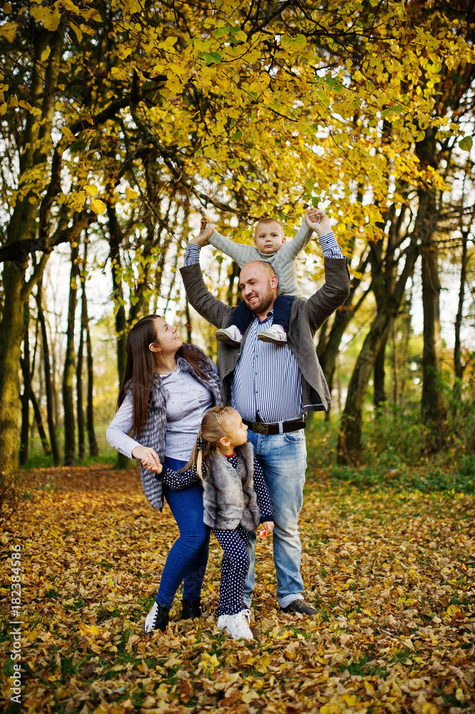 Happy caucasian family of mom dad and little girl with boy at majestic autumn fall forest.