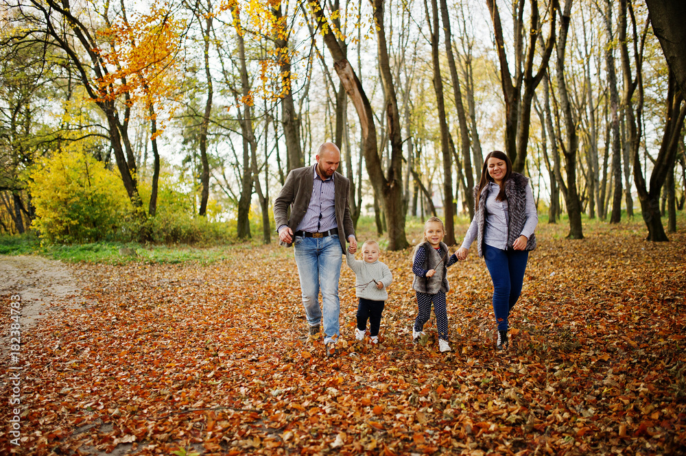 Happy caucasian family of mom dad and little girl with boy at majestic autumn fall forest.