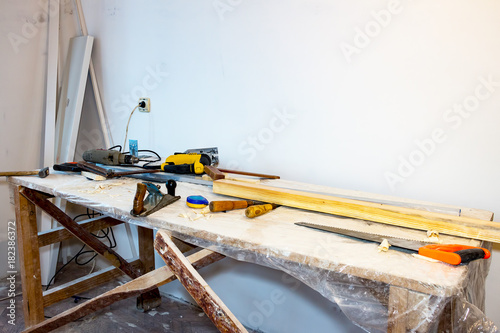 The table with the tools of a carpenter. On the table saw, planer, chisels, tape measure, electric jigsaw and a drill