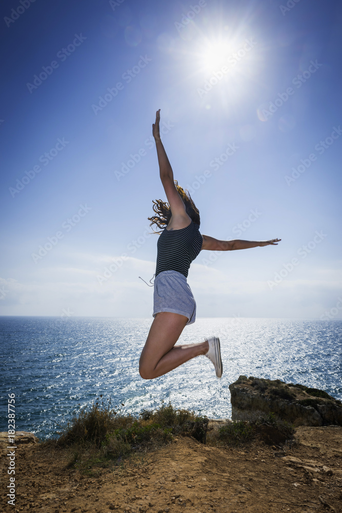 Junge Frau springt an der Küste der Algarve Junge Frau springt an der Küste der Algarve