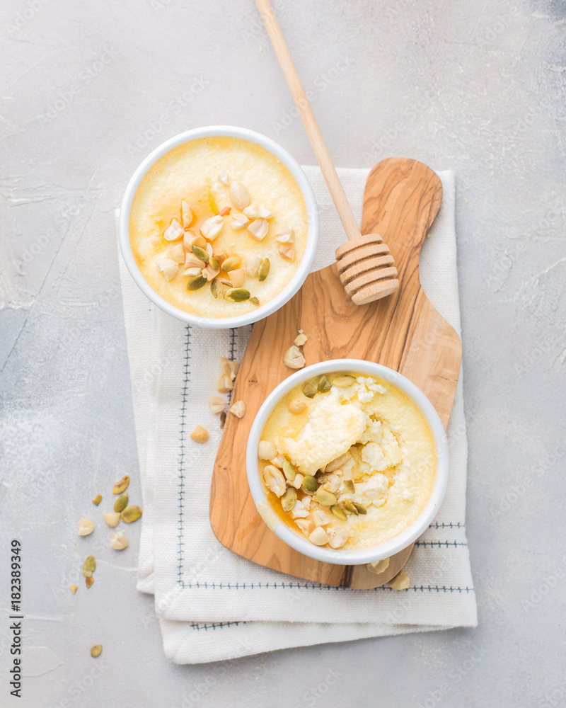 Classic cheesecake in small ceramic jars with nuts and honey on light concrete background and wooden board. The most delicious dessert or the perfect healthy breakfast!) Classic cheesecake in small ceramic jars with nuts and honey on light concrete background and wooden board. The most delicious dessert or the perfect healthy breakfast!)