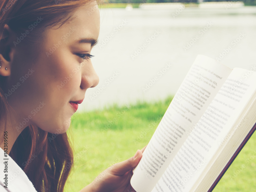 Fototapeta premium Close up face of young woman reading book at the park.
