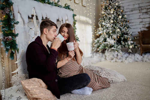 couple holding mugs against  christmas tree in room (1)