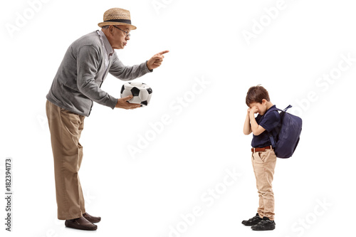 Mature man with a deflated football scolding a little boy