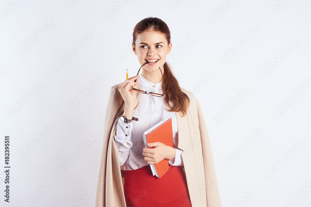 Young beautiful woman on a light background holds a notebook and glasses, teacher Young beautiful woman on a light background holds a notebook and glasses, teacher