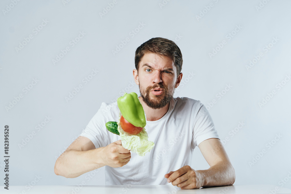 A man with a beard playing the guitar on a light background behind a hundredol keeps vegetables, diet, emotions, vegetarianism A man with a beard playing the guitar on a light background behind a hundredol keeps vegetables, diet, emotions, vegetarianism