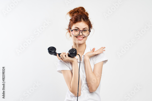Young beautiful woman on white isolated background holds the phone in glasses