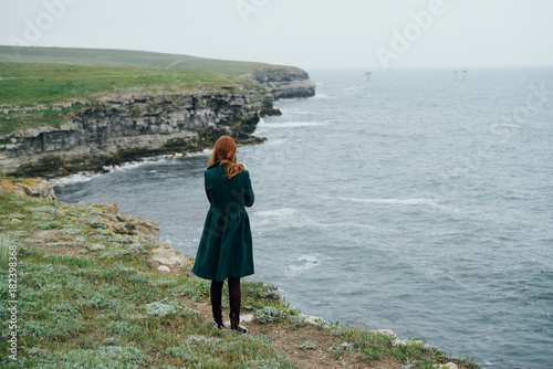 Woman on the cliff of the mountain by the sea, sadness, wind