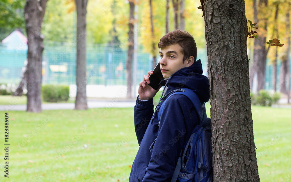 Portrait of Tenager guy with a smartphone talking phone. Park outdoor. Portrait of Tenager guy with a smartphone talking phone. Park outdoor.