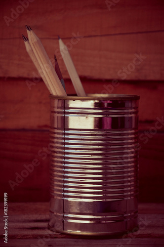 Pencils in a tin can on a wooden floor