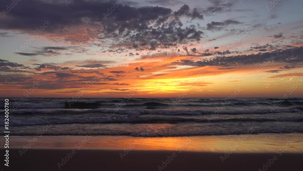 Waves washing ashore with sunset over lake - beautiful clouds in the sky and reflection of sunset on water on beach Waves washing ashore with sunset over lake - beautiful clouds in the sky and reflection of sunset on water on beach